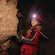 A child wearing a helmet and headlamp examining rock formations inside a cave